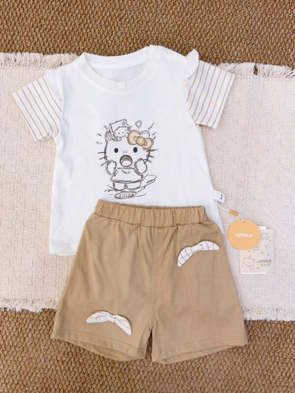 White cartoon-cat short-sleeve top with beige-brown striped sleeves, paired with khaki shorts featuring striped bow details.