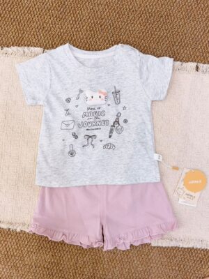 Light heather-grey short-sleeve top with a cartoon cat and small motifs, paired with pink ruffle-hem shorts.