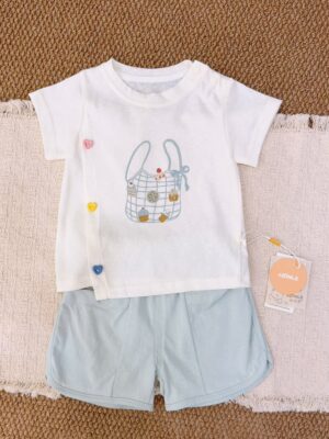 White top with a checked bag and dessert print and three colourful heart details at the side front, paired with pale blue curved-hem shorts.