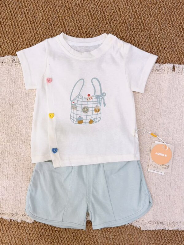 White top with a checked bag and dessert print and three colourful heart details at the side front, paired with pale blue curved-hem shorts.