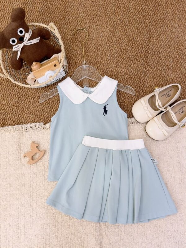 Light blue sleeveless top and pleated skirt laid flat, with a white Peter Pan collar, white waistband and a dark horse-and-rider chest motif.