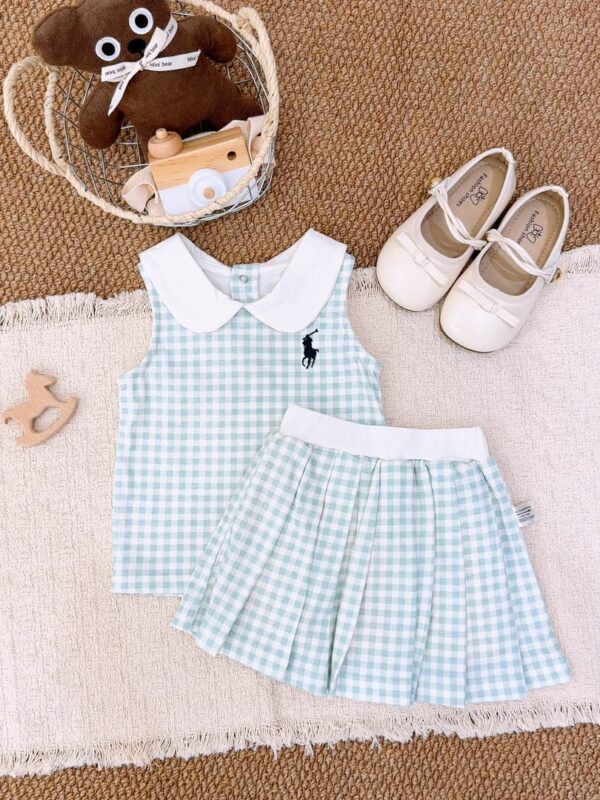 Pale blue-green and white gingham sleeveless top and pleated skirt, with a white Peter Pan collar, white waistband and a dark horse-and-rider chest motif.