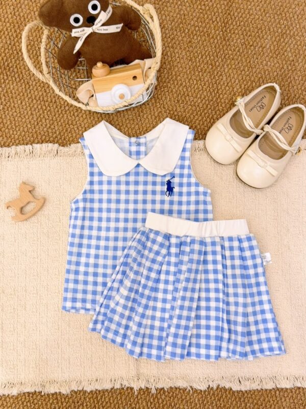 Blue and white gingham sleeveless top and pleated skirt, with a white Peter Pan collar, white waistband and a dark blue horse-and-rider chest motif.