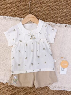 White rabbit-and-flower print short-sleeved top with a rounded collar and lace-edged rabbit chest panel, paired with beige-brown shorts featuring a white flower and green leaves.