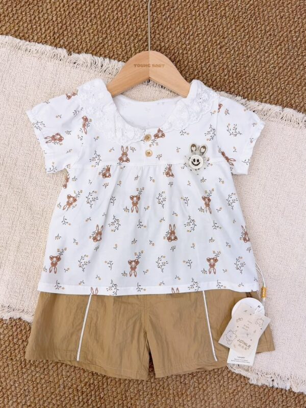 White short-sleeved top with brown rabbits and floral sprigs, an embroidered ruffle collar, two brown buttons and a rabbit-face decoration, paired with khaki-brown shorts with white piping.