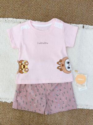 Pale pink crew-neck short-sleeved top with white shoulder lace, snap buttons and cartoon graphics at the lower sides, paired with dusty pink floral shorts.