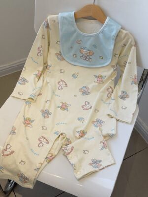 Pale cream long-sleeved romper with a light blue elephant bib, printed with elephants, pink rocking horses and small winged characters.